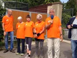 Helferinnen und Helfer in orangefarbenen T-Shirts bei einer Veranstaltung im Freien