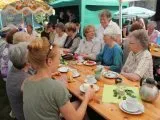 Gemeindeglieder beim Kaffeetrinken an einer langen Tafel im Freien