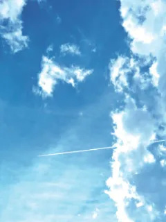 Blauer Himmel mit weißen Wolken und einem Kondensstreifen