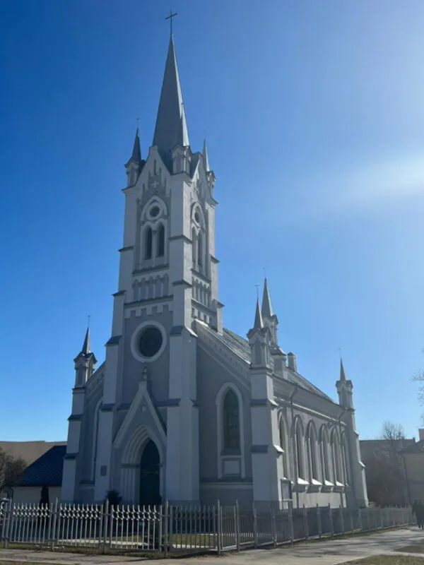 Die weiße evangelisch-lutherische Kirche in Grodno mit spitzem Turm vor blauem Himmel